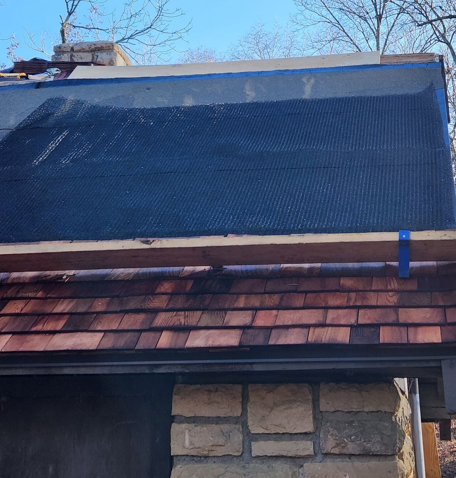 Technician measuring and photographing damaged shingles on a roof in Momence